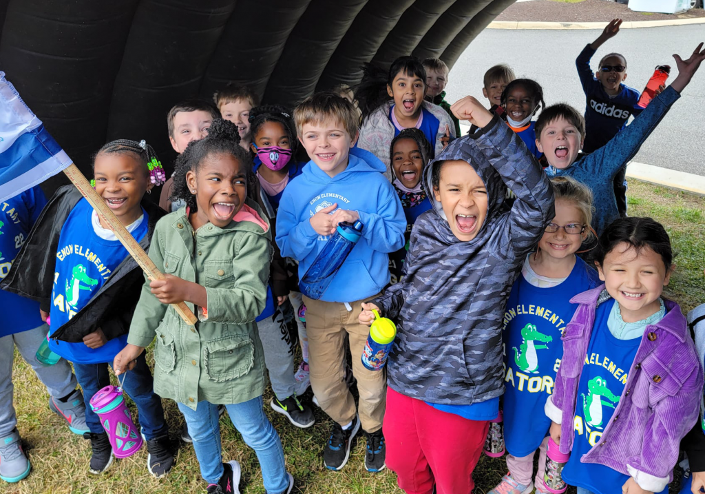 Large group of students under a blow up tunnel posing for a group photo.