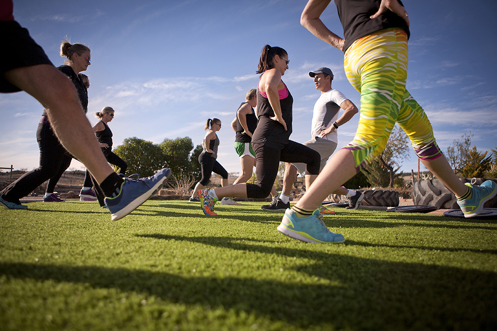 A group of people exercising and stretching in the Spanish sunshine with personal trainer.
