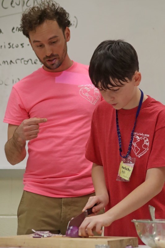 Teacher watching student cutting an onion