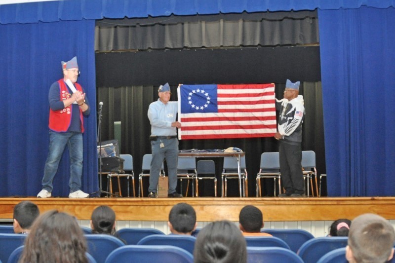 Three veterans displaying a historic American flag