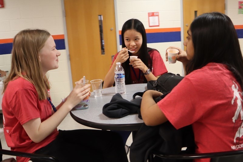 Three girls smiling and eating out of small cups