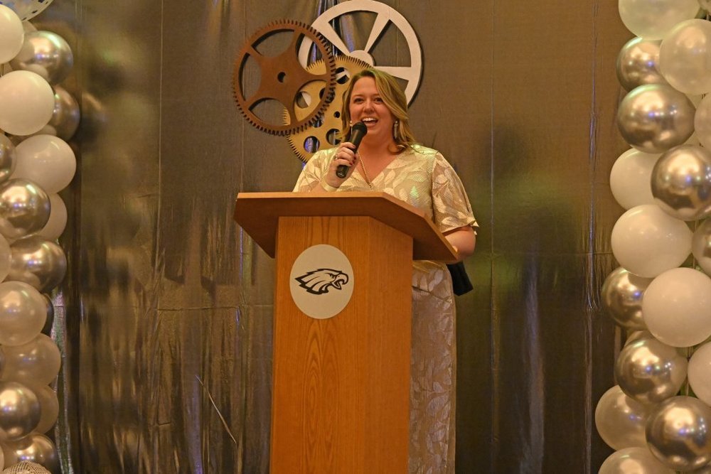 Katy Clarke, smiling, delivering speech behind a podium