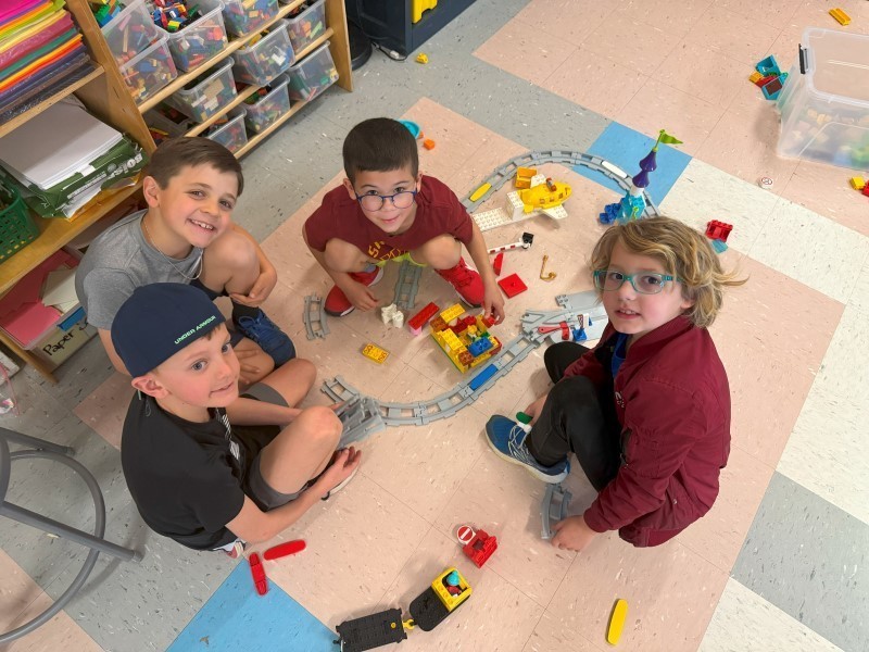 Four children on the floor playing with the Duplo sets