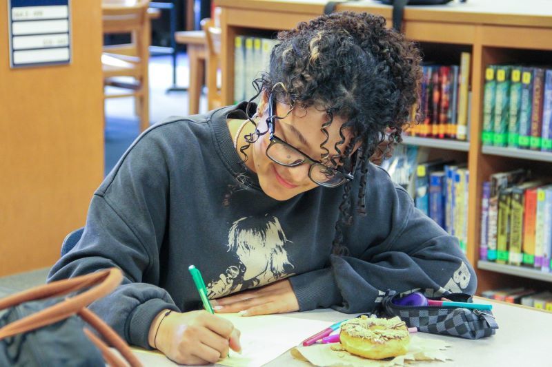 A student drawing a hand-written card