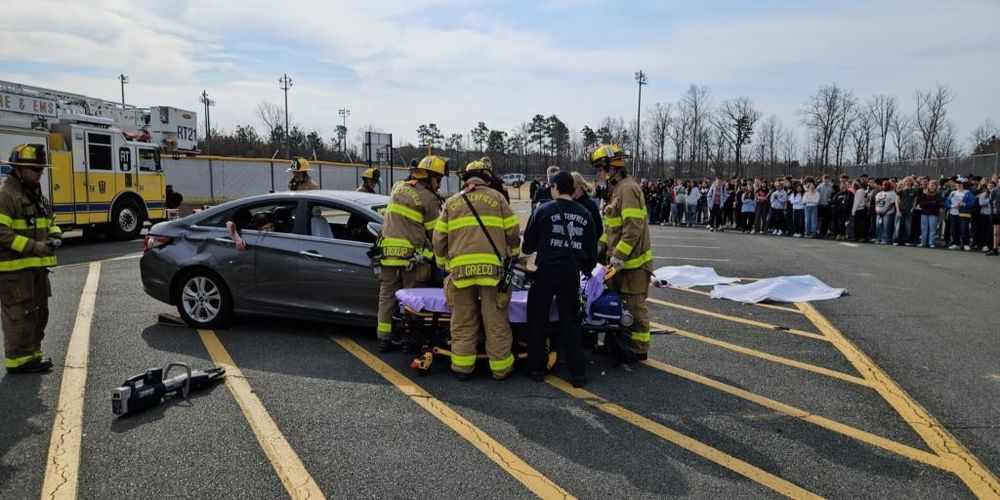 A group of students watching a depiction of the aftermath of a car crash.