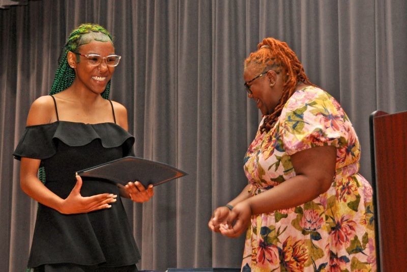 Student smiling, holding a certificate