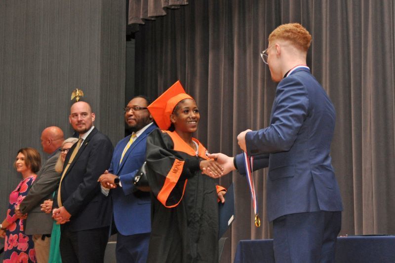 Student in a cap and gown shaking hands