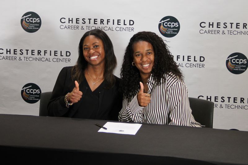Two young women smiling with thumbs up