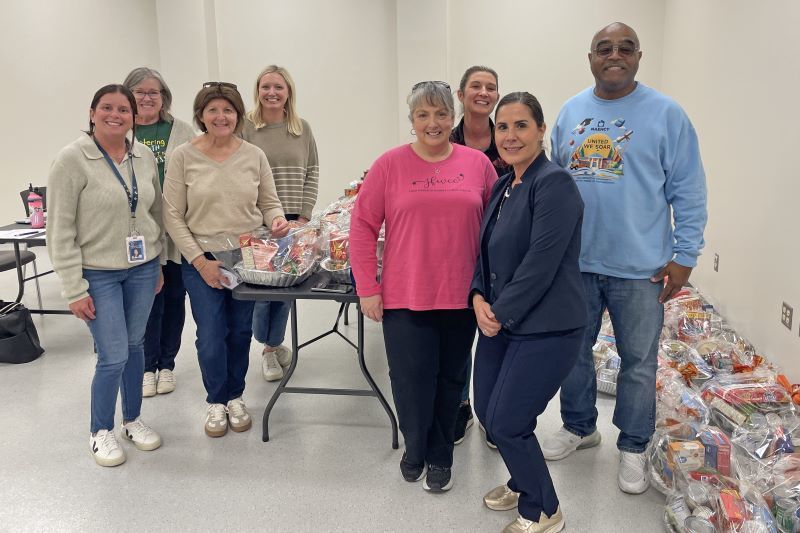 A group of people smiling around a pile of donations