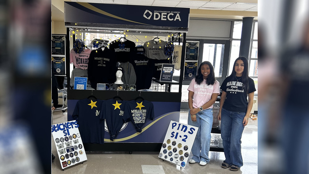 Two studetns standing next to a kiosk with school spirit items