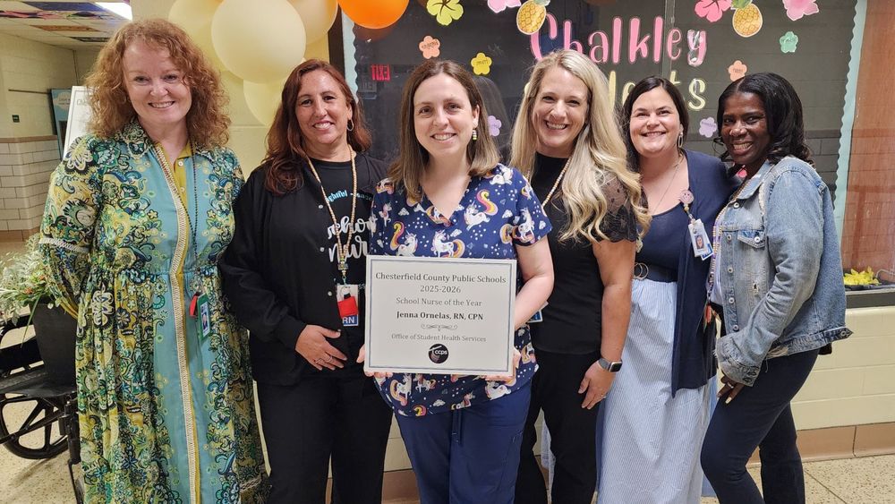Jenna Orenalas holding a congratulatory placard, with other employees