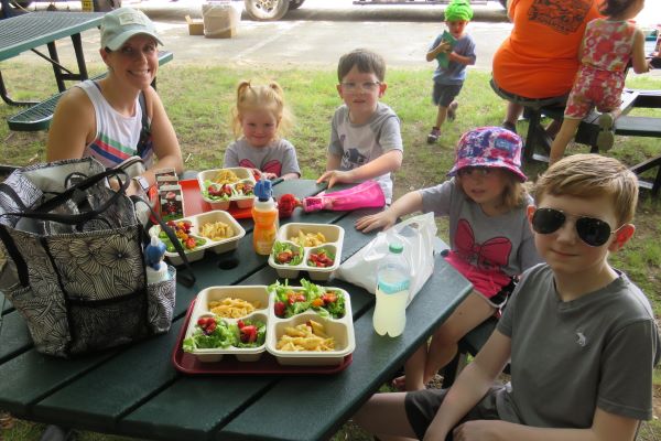 Family picnic table with food and children.
