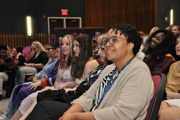 A woman smiling, watching in the audience