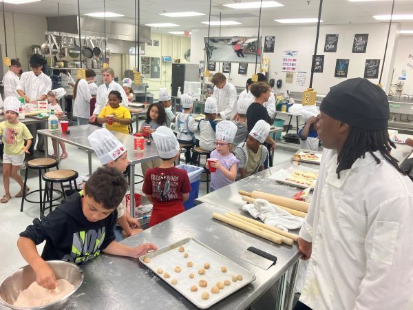 A large kitchen full of young students in chefs hats