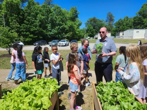 Children gathered outdoors learning about gardening.