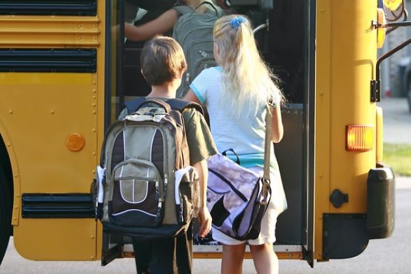 Kids boarding a yellow school bus with backpacks. Kids boarding a yellow school bus with backpacks.
