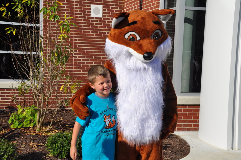 Child posing with a fox mascot